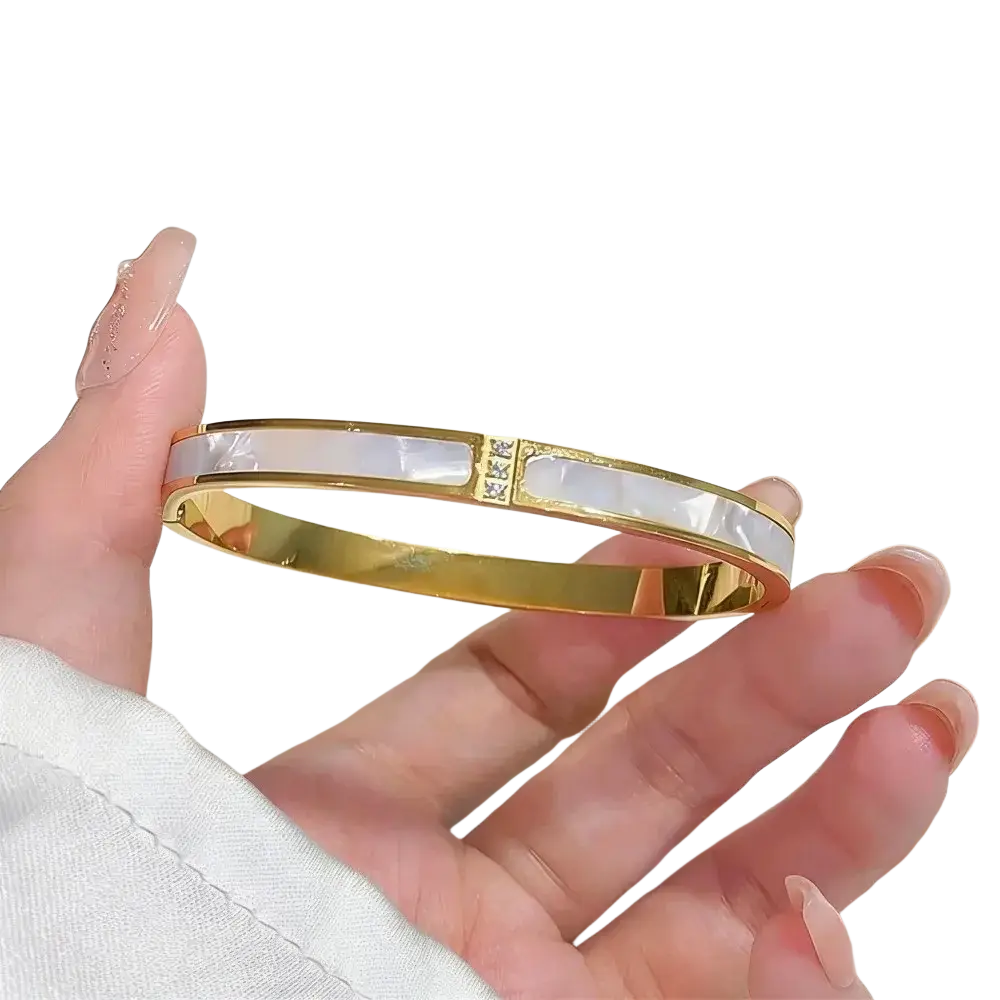 Gold-toned stainless steel bangle bracelet for women with a white mother-of-pearl panel and clear crystal accents