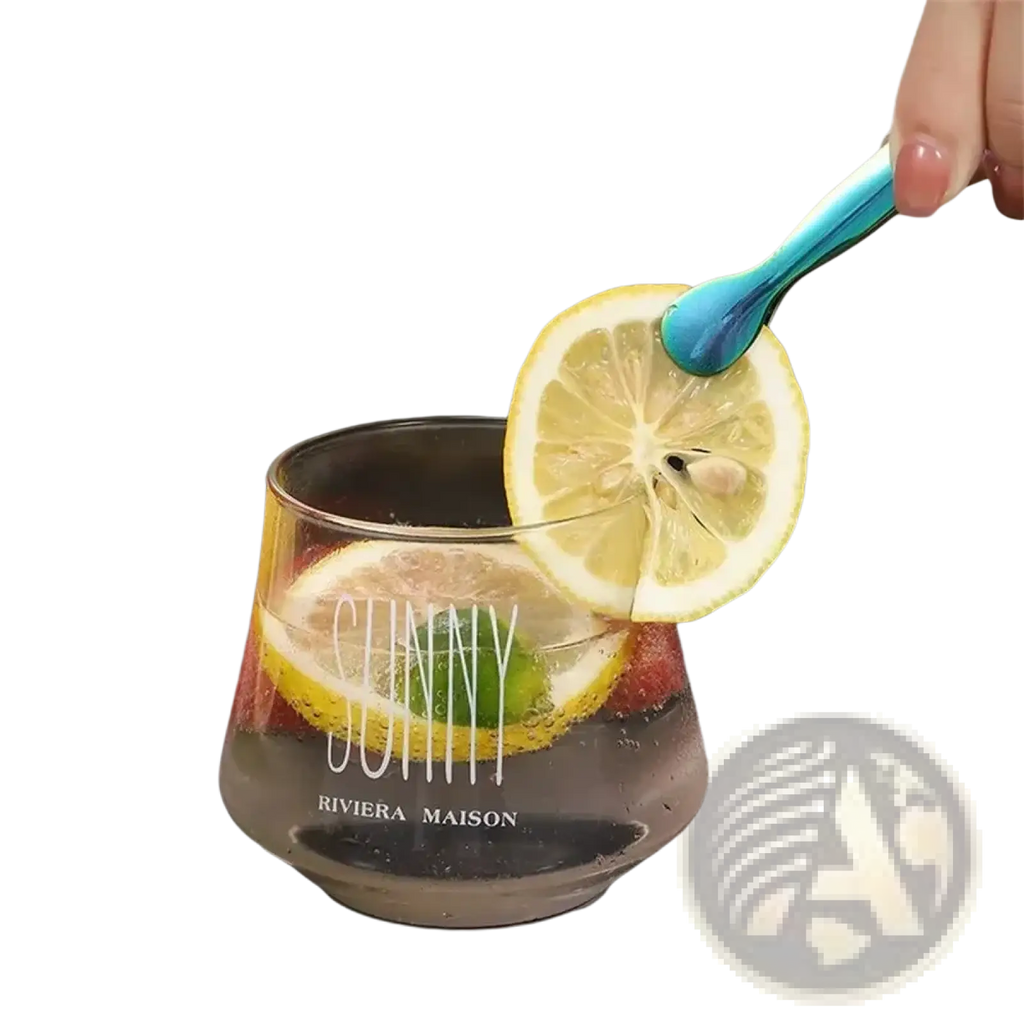 A clear glass tumbler with sunny and riviera maison print filled with a sparkling beverage and lemon slices next to stainless steel mini ice tongs for kitchen and bar
