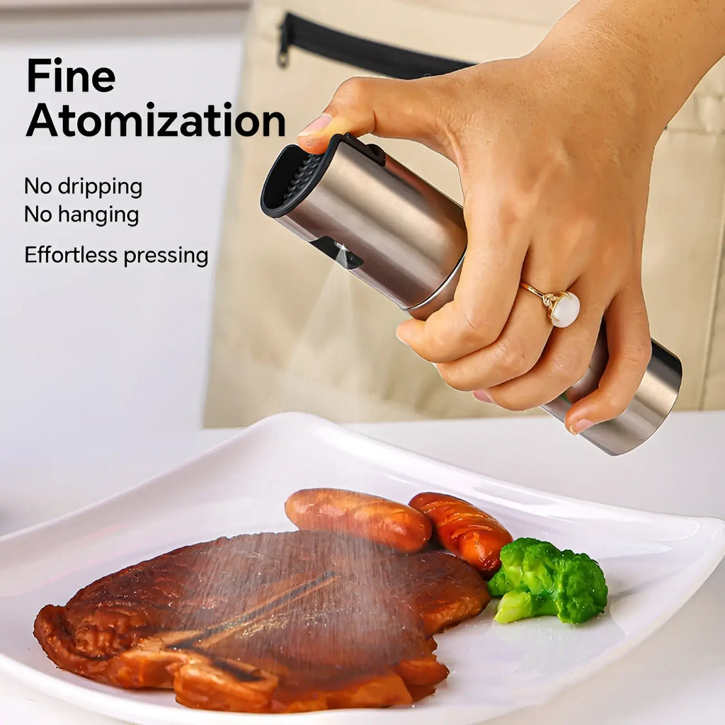 Stainless steel oil sprayer with measurement scale featuring black rubberized grip and nozzle for precise seasoning application