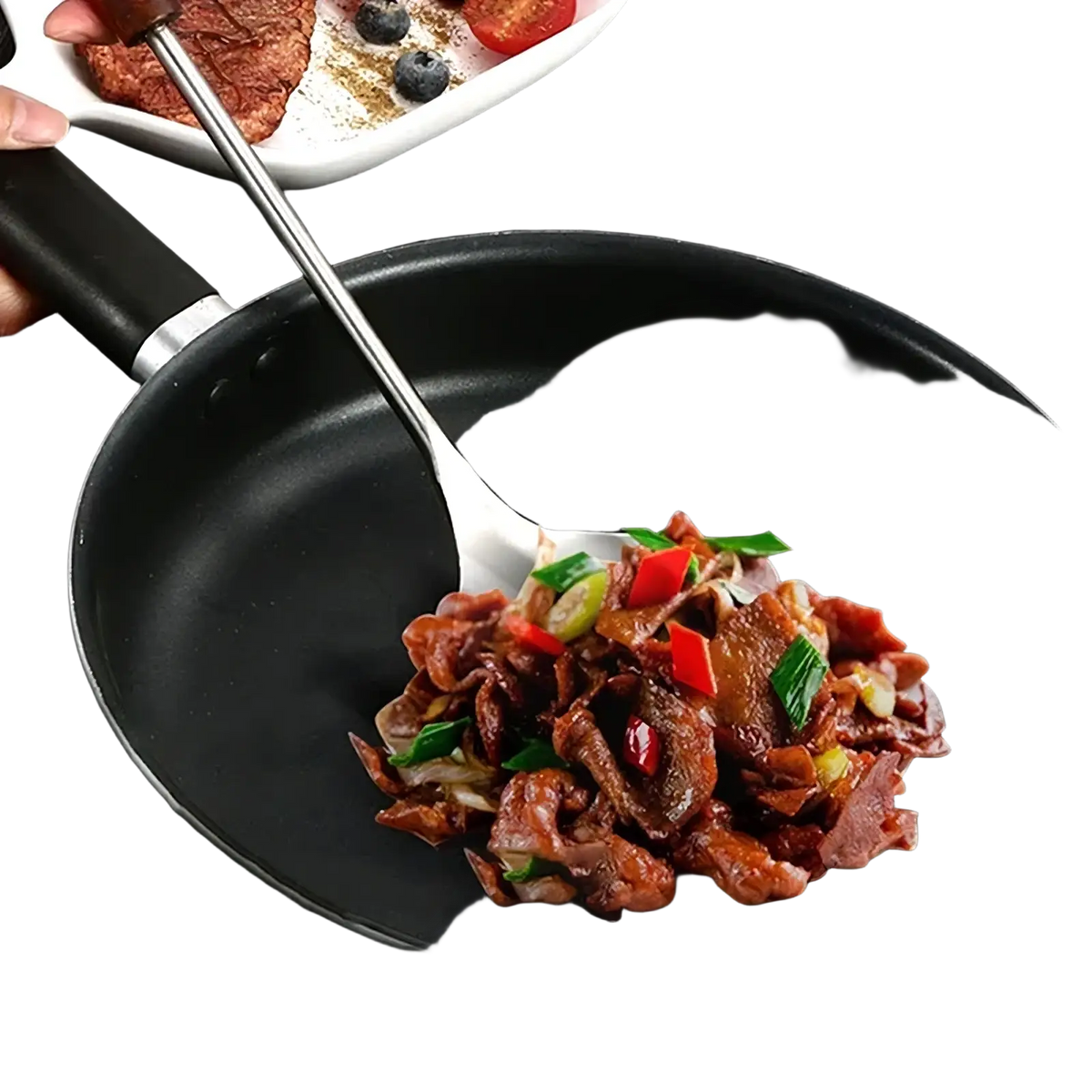 Black non-stick frying pan with silver rim containing cooked meat and vegetables alongside stainless steel wok spatula set