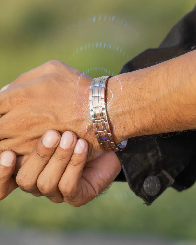 A sleek silver-toned stamped chain magnetic copper bracelet with segmented design for targeted relief worn on arm