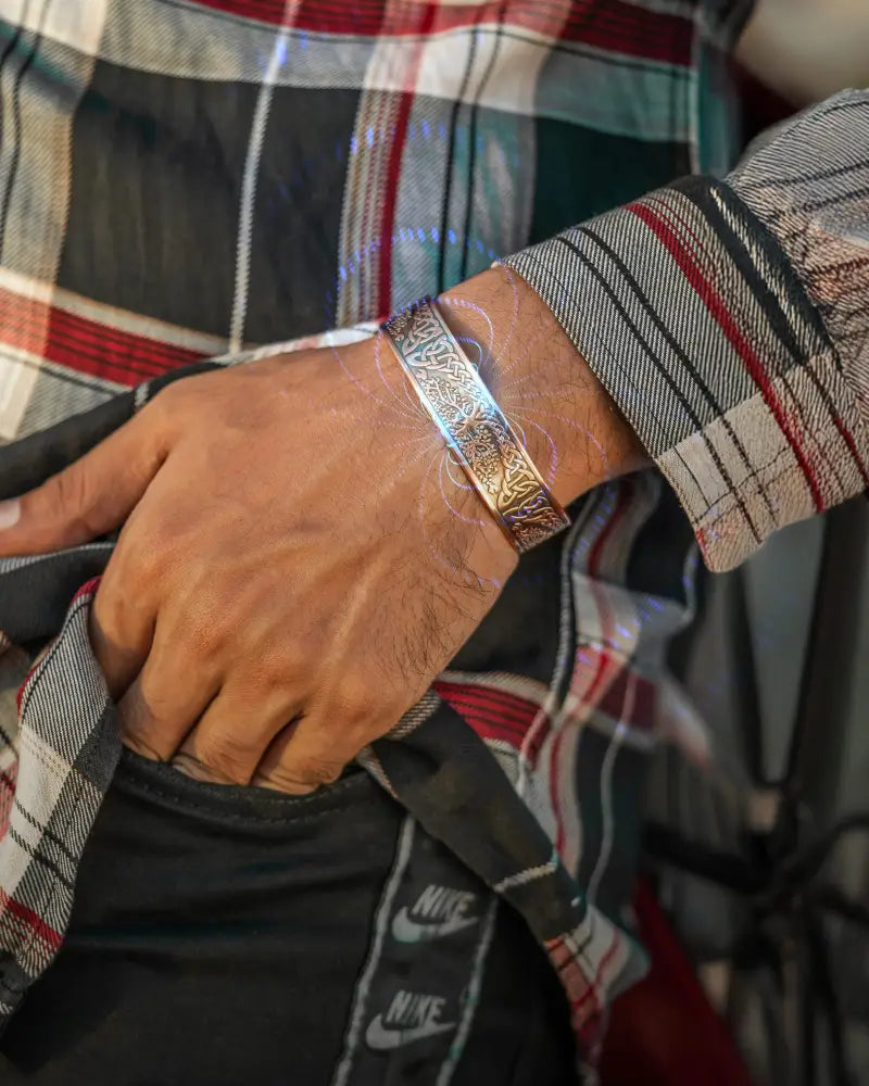 A sleek silver-toned irish tree engraved magnetic copper cuff bracelet with intricate patterns on the wrist