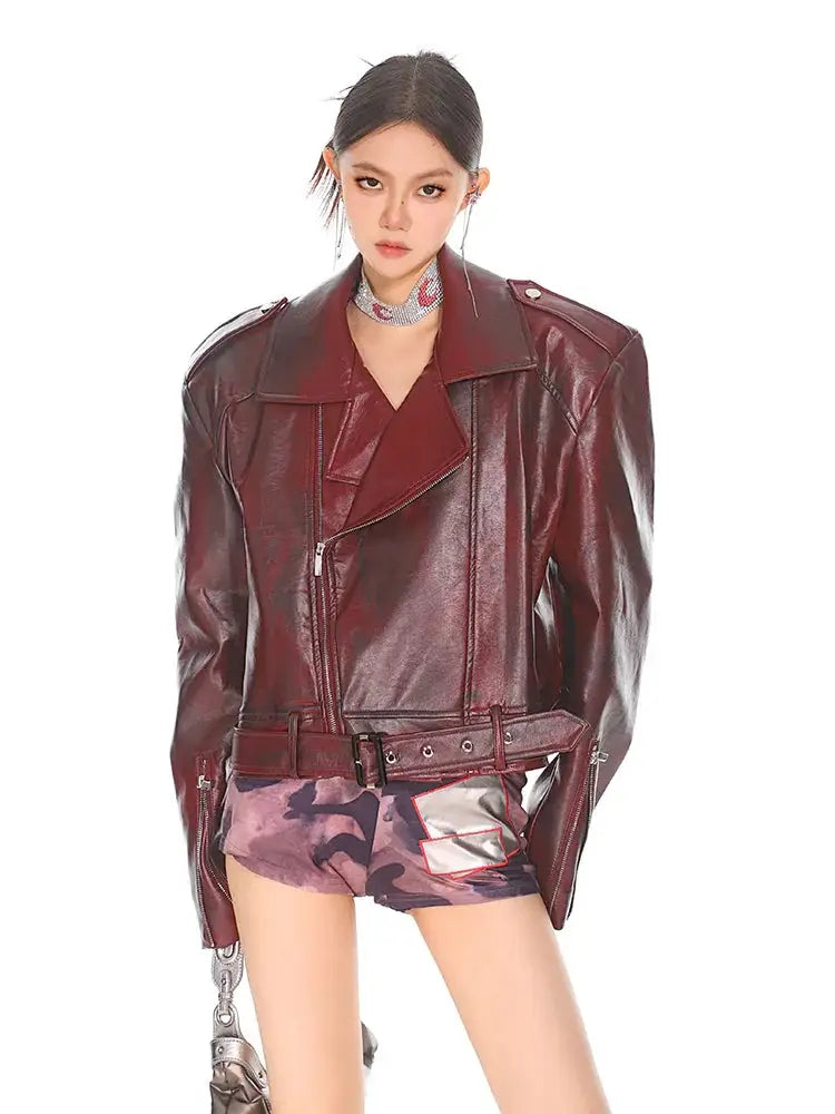 Glossy burgundy leather biker jacket with belted waist and structured shoulders for a stylish moto look
