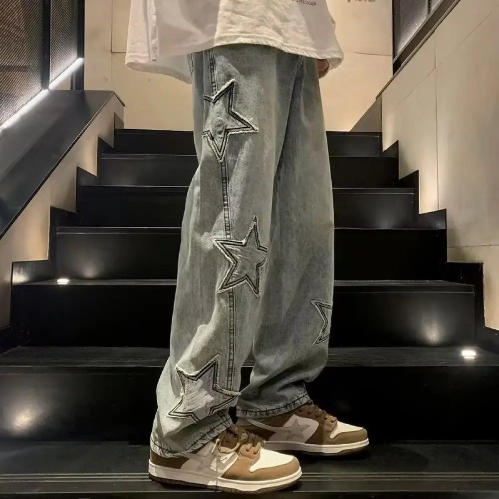 Men’s y2k light-wash denim jeans with bold stitched star appliqués down the outer leg in a baggy streetwear style