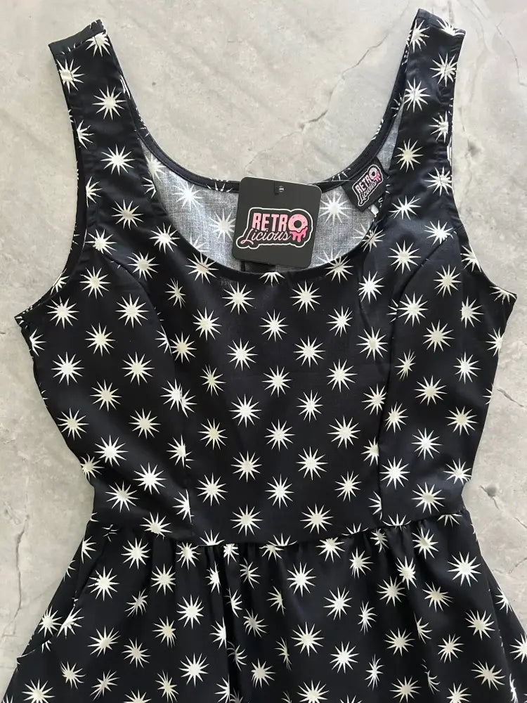 Black sleeveless cotton fit and flare dress with white starburst pattern scoop neckline and gathered waist with pockets