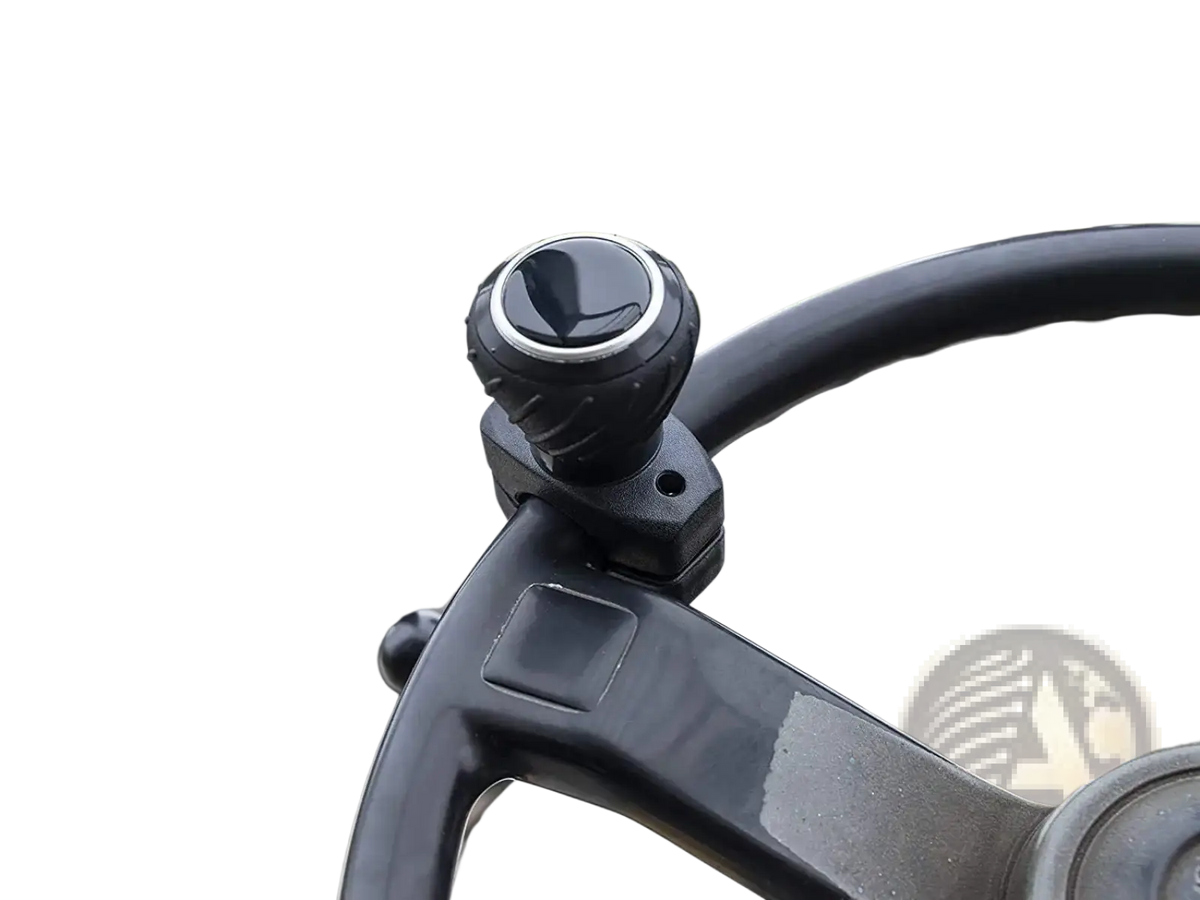 Black textured ergonomic steering wheel spinner knob with silver accent ring mounted on forklift steering column