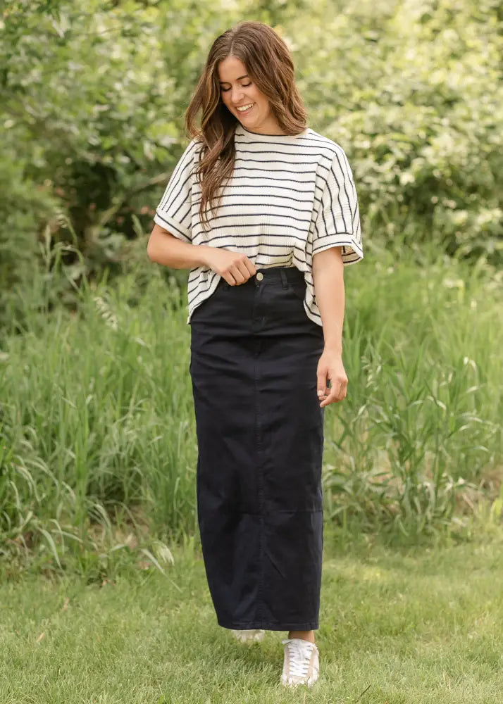 Black high-waisted midi skirt with straight cut and subtle front seam detail paired with stella navy embroidered maxi denim skirt with back slit