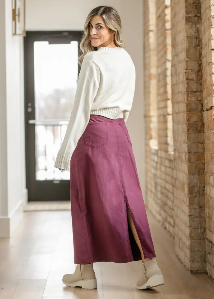 Stella Orchid high waisted purple denim maxi skirt with front slit and back pocket shown from the back side