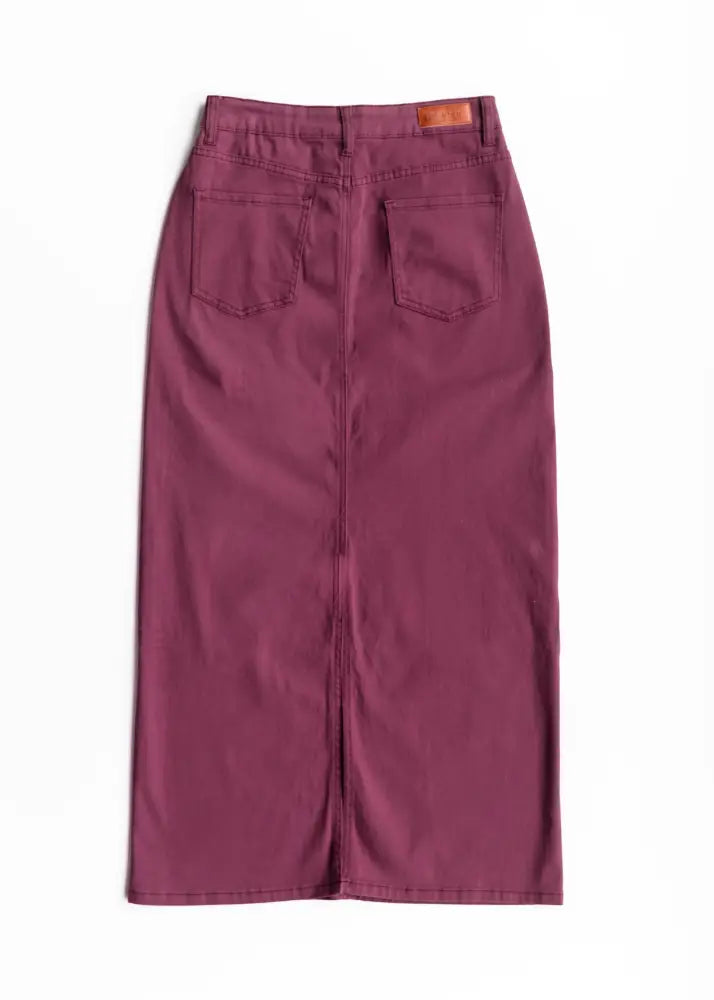 Back side of a stella orchid high waisted purple denim midi skirt in maroon with two back pockets and brown leather patch
