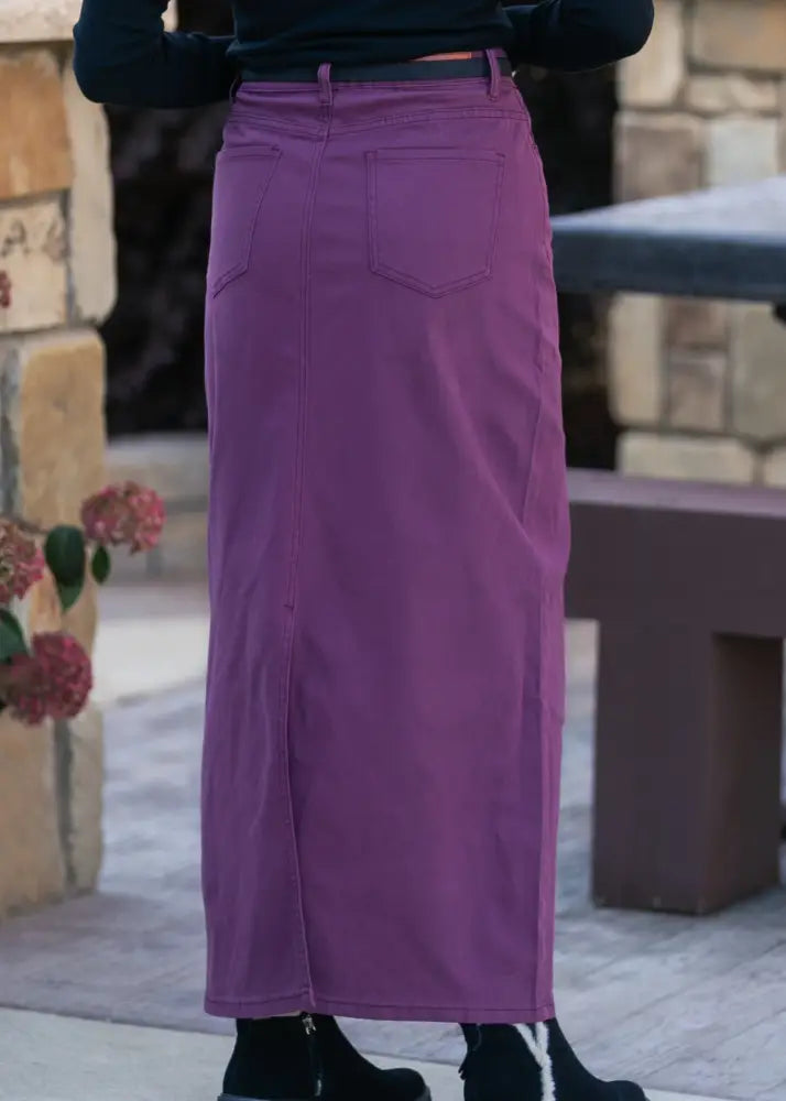 Back view of stella orchid high waisted purple denim maxi skirt with two pockets and central front slit