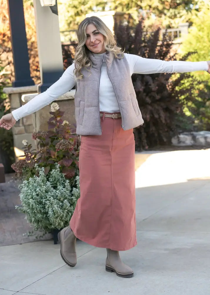 A soft gray quilted vest with high collar and front pockets worn over a white top paired with stella sienna high waisted stretch denim maxi skirt