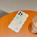 Back side of a 3d pastel floral textured silicone phone case with cream base and 3d light blue pink and lavender flowers