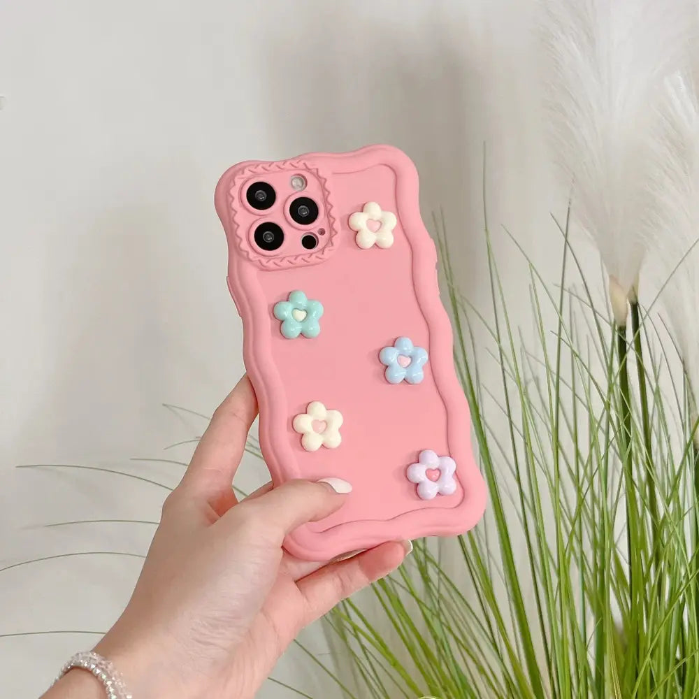 Pink silicone phone case with pastel-colored 3d flower embellishments shown from the back side