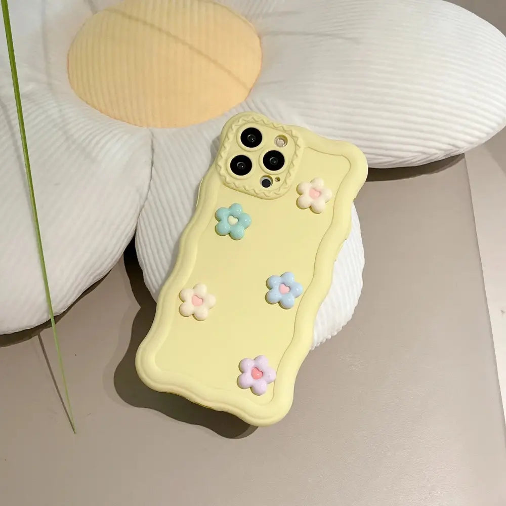 Pastel yellow silicone phone case with raised 3d soft blue and pink floral texture shown from the back side