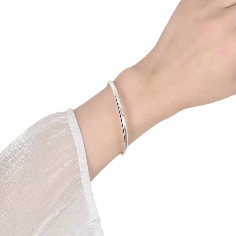 A sleek sterling silver 4mm bangle bracelet for women worn on a wrist showcasing its minimalist design