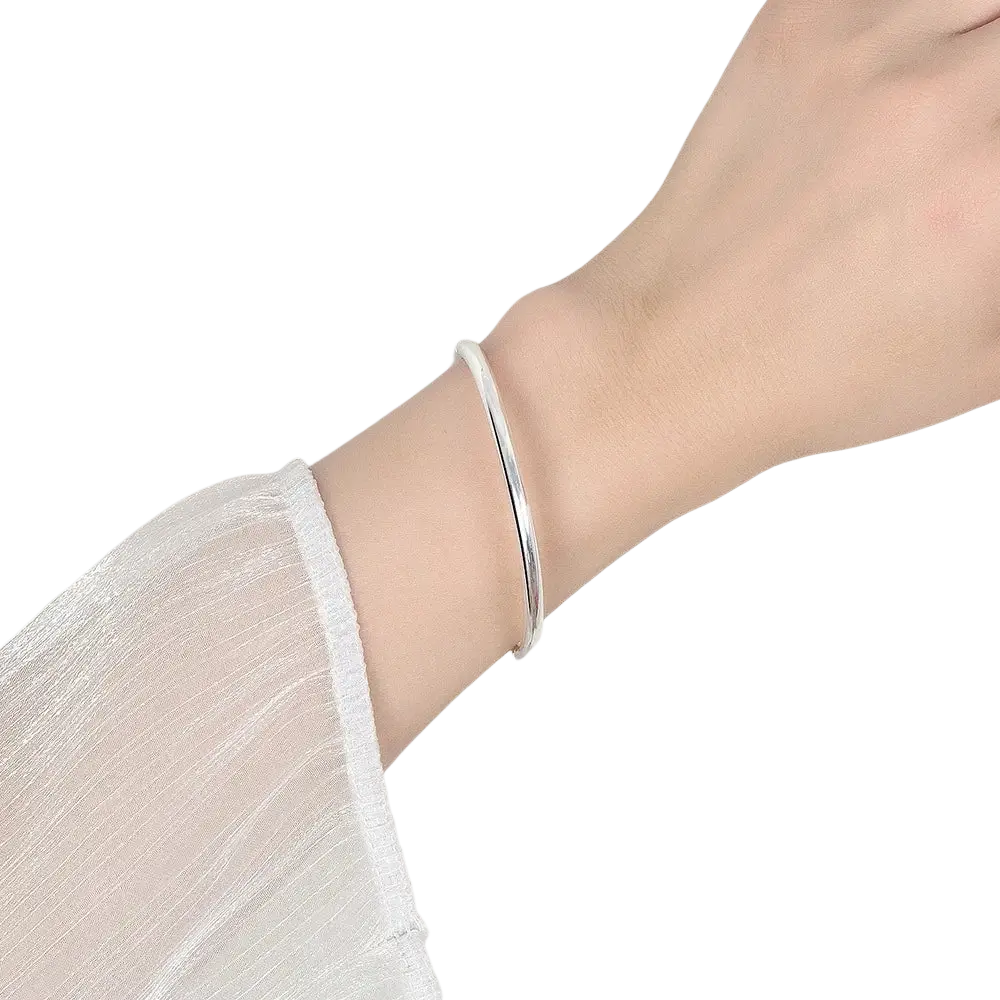 A sleek minimalist sterling silver 4mm hinge bangle bracelet in silver worn on a wrist for women