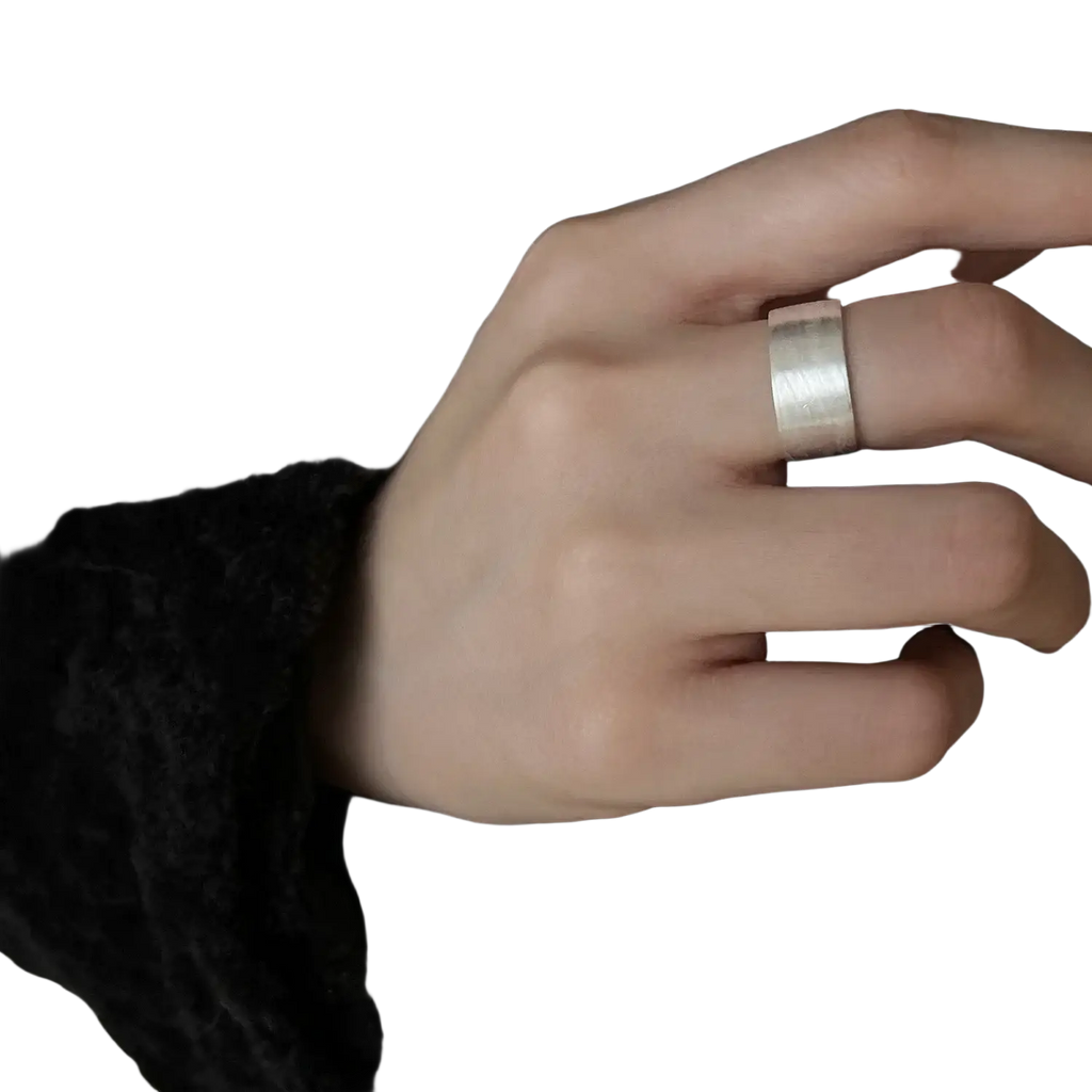 A sleek silver-toned sterling silver beaded open ring with a textured surface worn on a finger