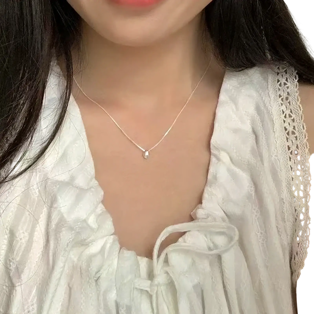 A delicate sterling silver geometric pendant necklace featuring a small teardrop-shaped silver pendant