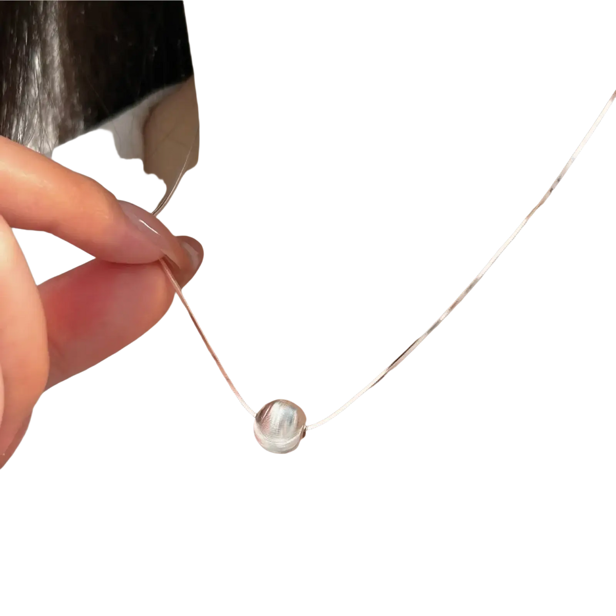 A sleek silver spherical sterling silver pendant necklace with a delicate chain and subtle textured surface
