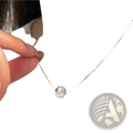 A sleek silver spherical sterling silver pendant necklace with a delicate chain and subtle textured surface