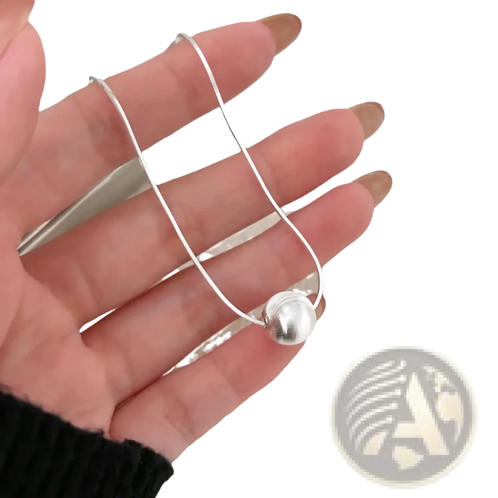 Sterling silver pendant necklace featuring a silver snake chain with a polished spherical pendant minimalistic design