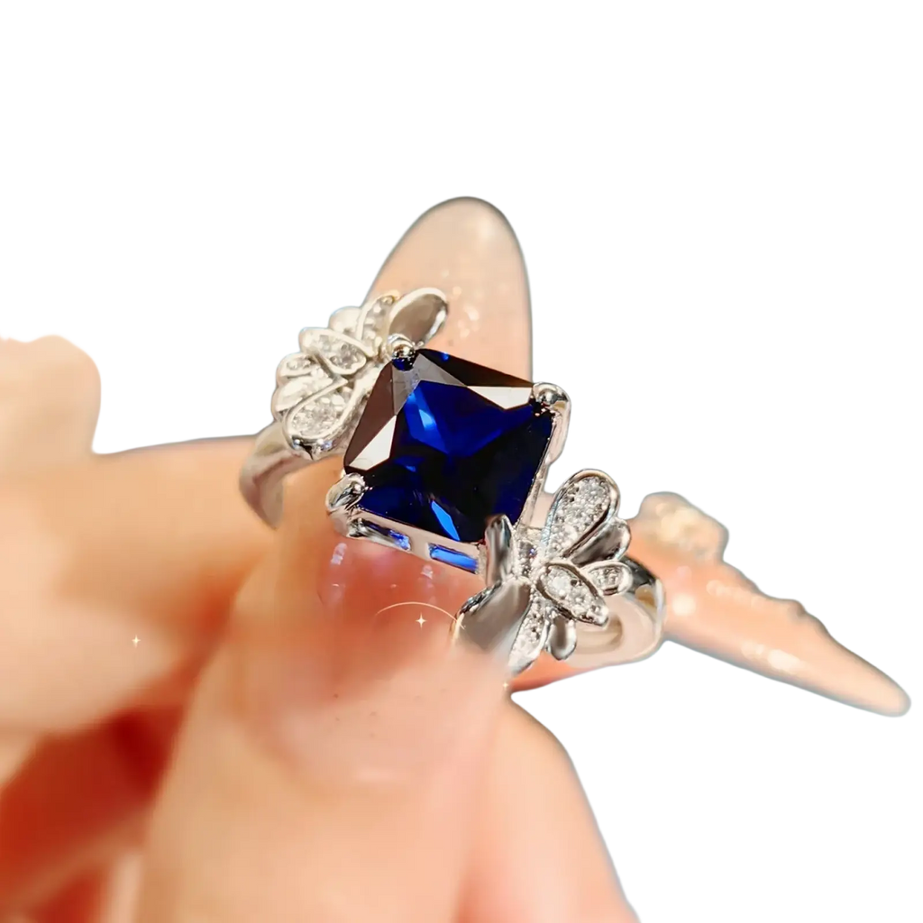 Sterling silver ring for women with a square-cut deep blue sapphire and butterfly motifs with clear stones