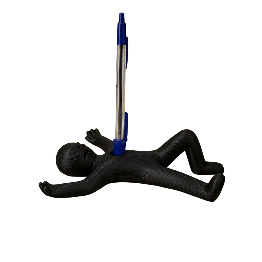 Black plastic stick figure pen holder desk organizer shaped like a sleeping figure holding a blue ballpoint pen upright