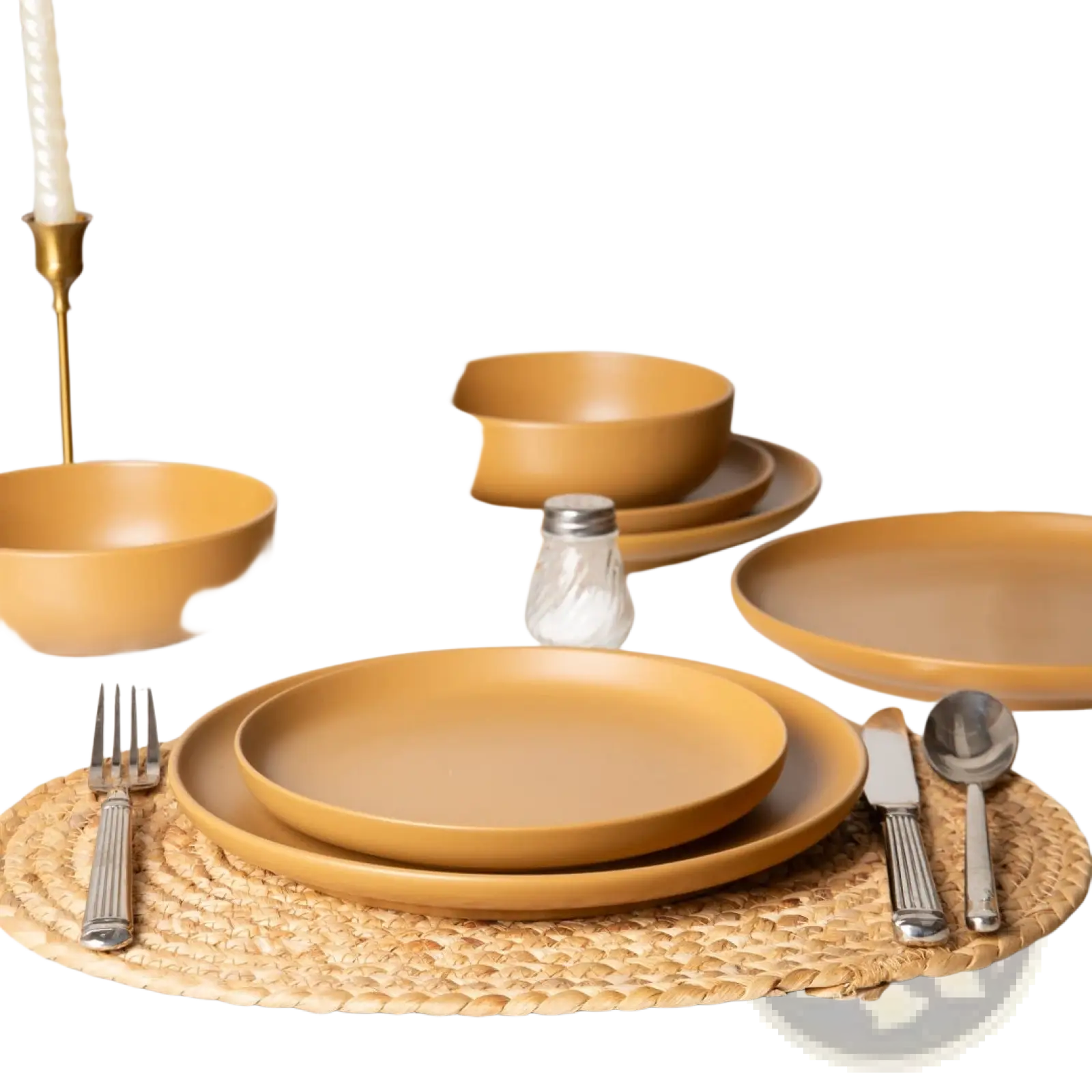 Warm mustard-yellow stoneware dinnerware set with matte glaze includes bowls plates and cutlery on a woven placemat