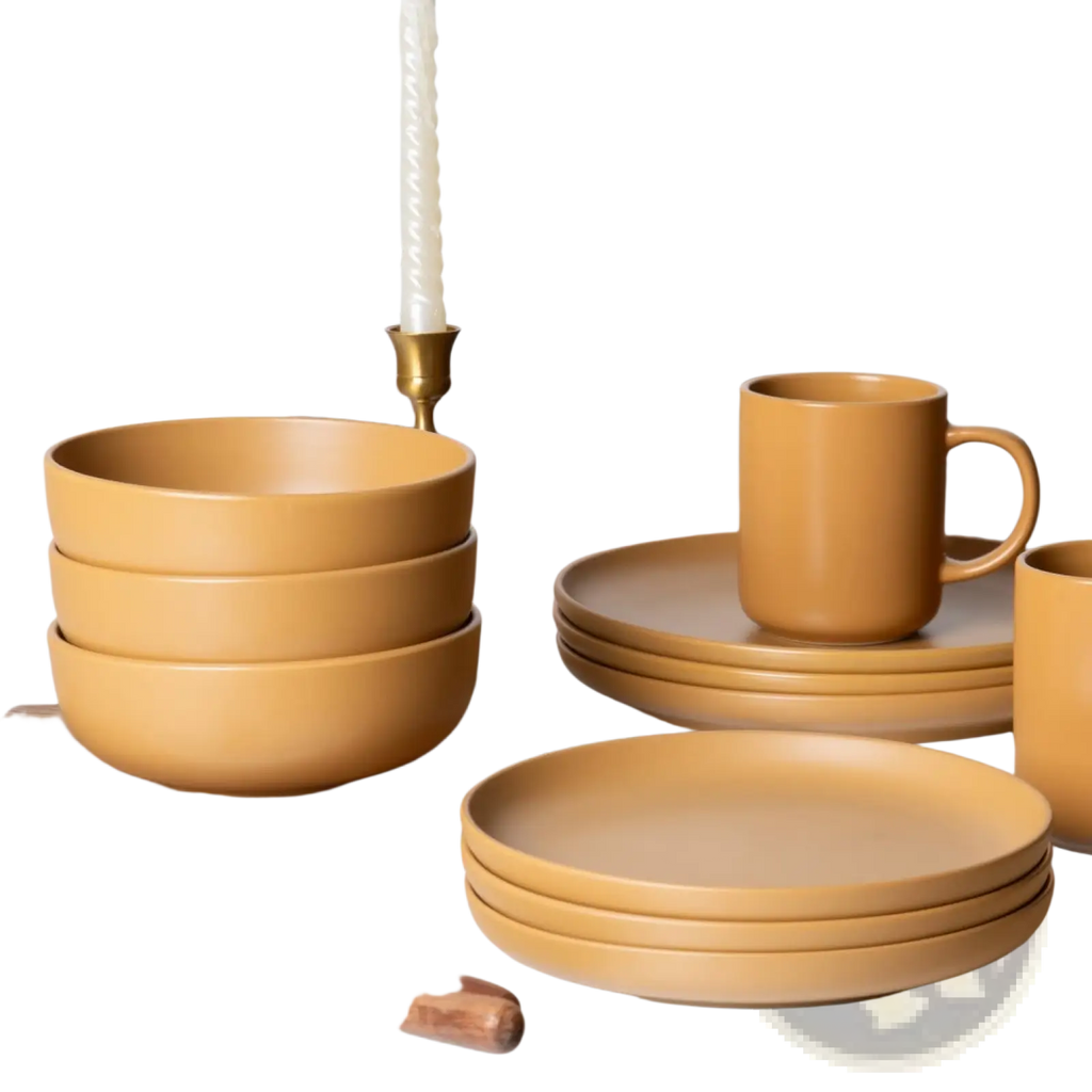 Set of 12-piece matte glaze mustard-yellow stoneware dinnerware with bowls plates and mugs on wooden surface