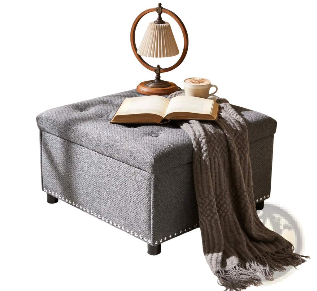 Gray tufted square storage ottoman with textured fabric finish and decorative nailhead trim along the base
