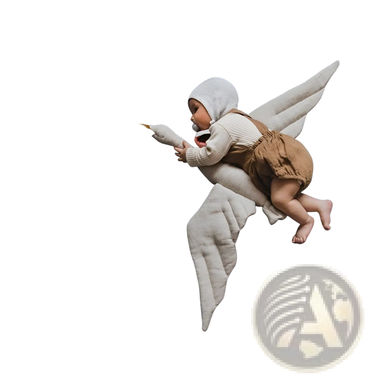 A baby in a white knit hat and beige overalls lies on a stork plush toy white swan animal pillow with embroidered wings