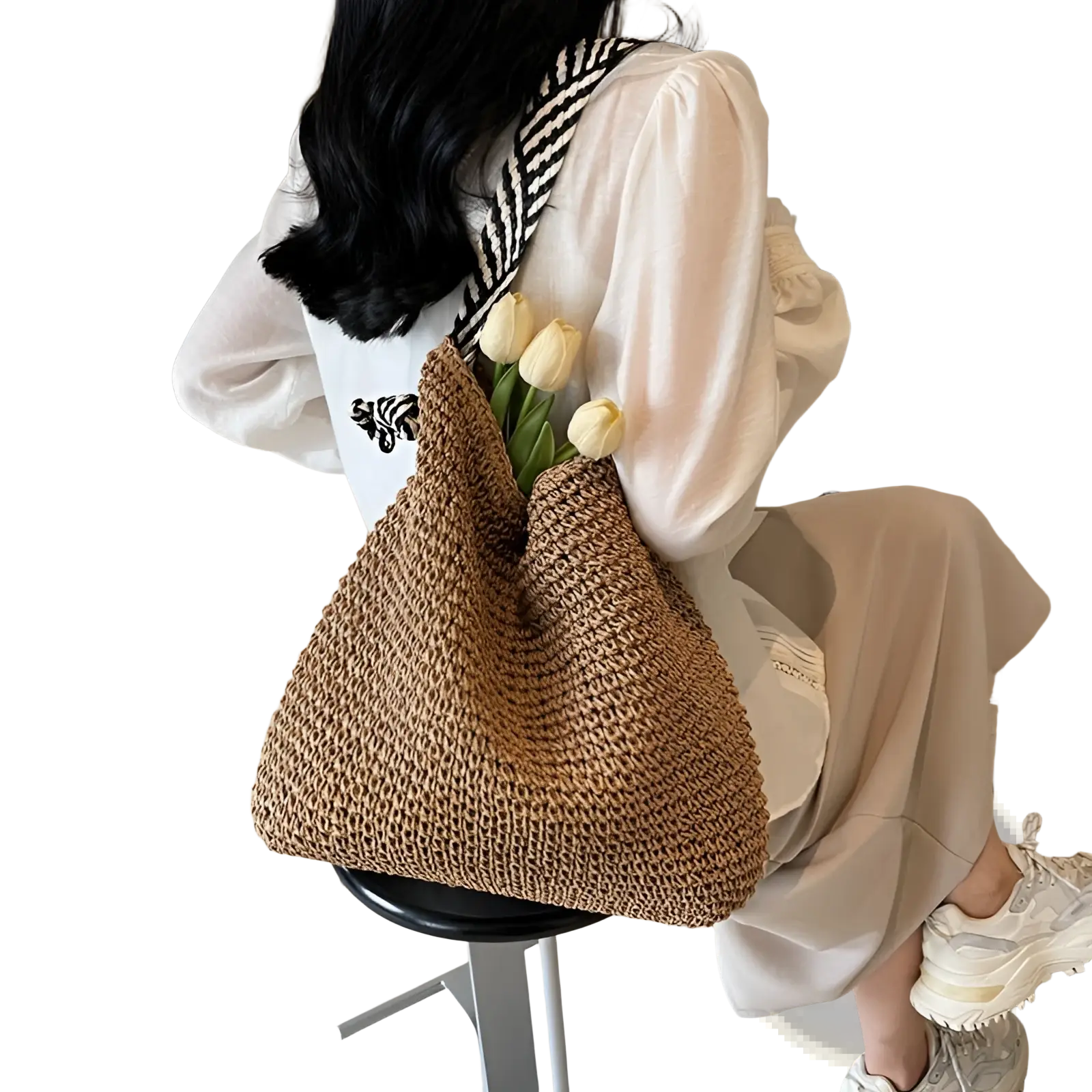 A woven beige straw tote bag with black and white striped bow handles featuring a relaxed textured design