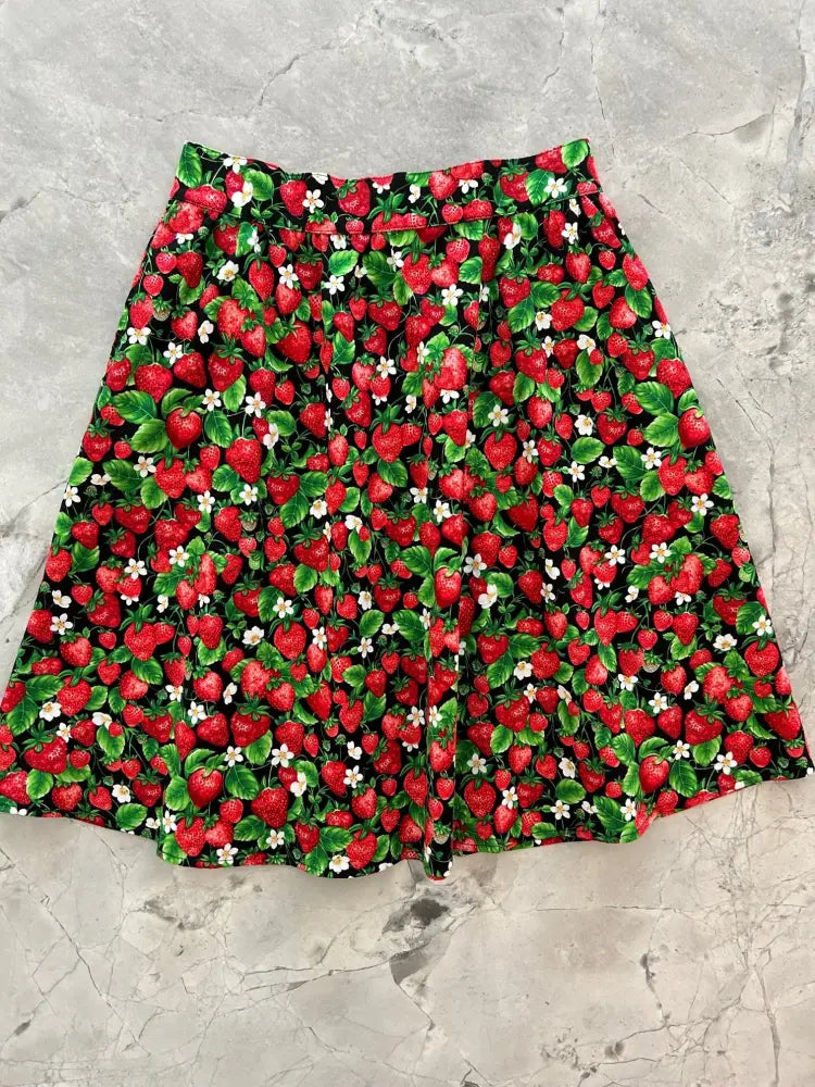 A vintage strawberry print cotton a line skirt with pockets featuring red strawberries and green leaves on dark fabric