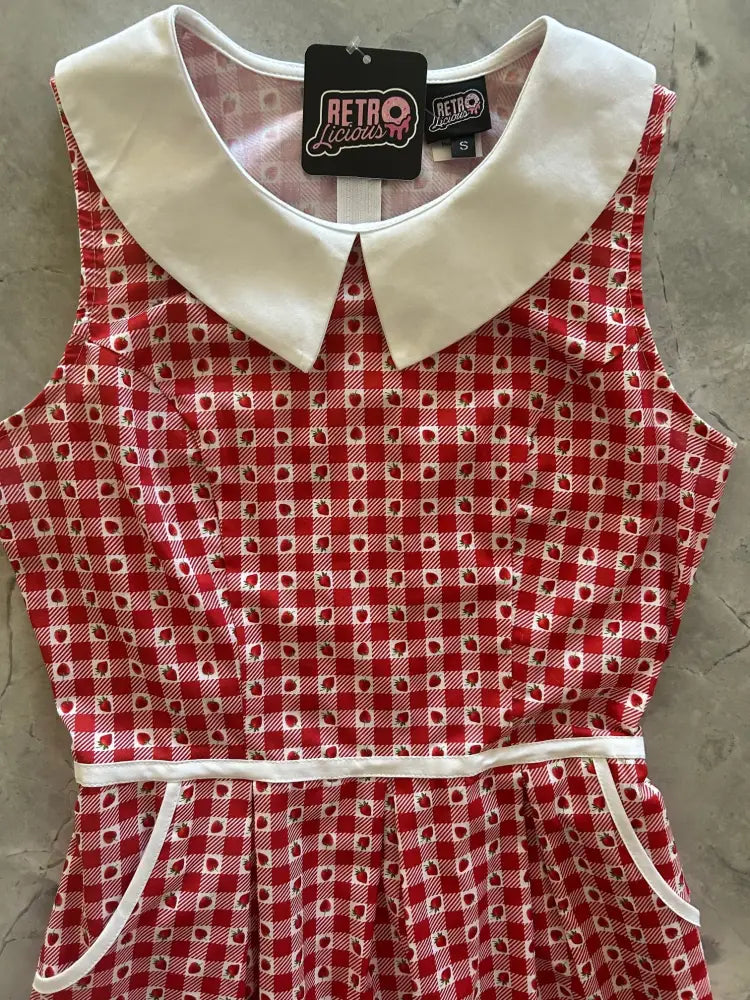 Retro strawberry gingham dress with red and white pattern, white peter pan collar, elastic waistband, and pocket trim