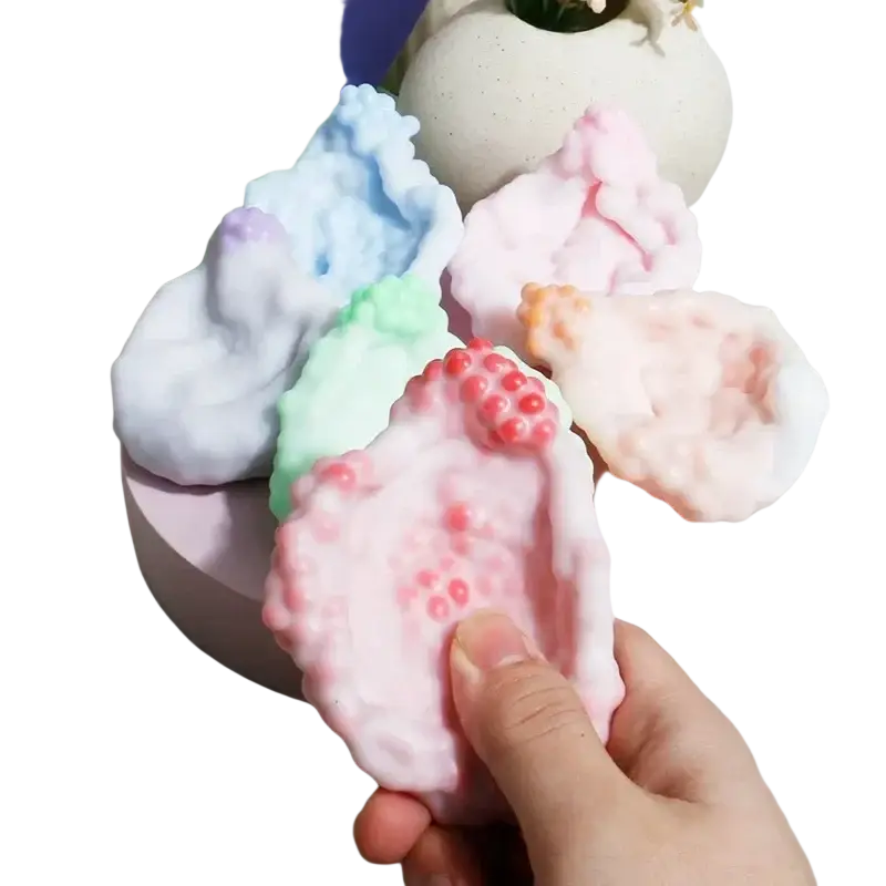 A soft pink stress ball fidget toy with a bumpy texture and small red bead-like details for asmr crunch