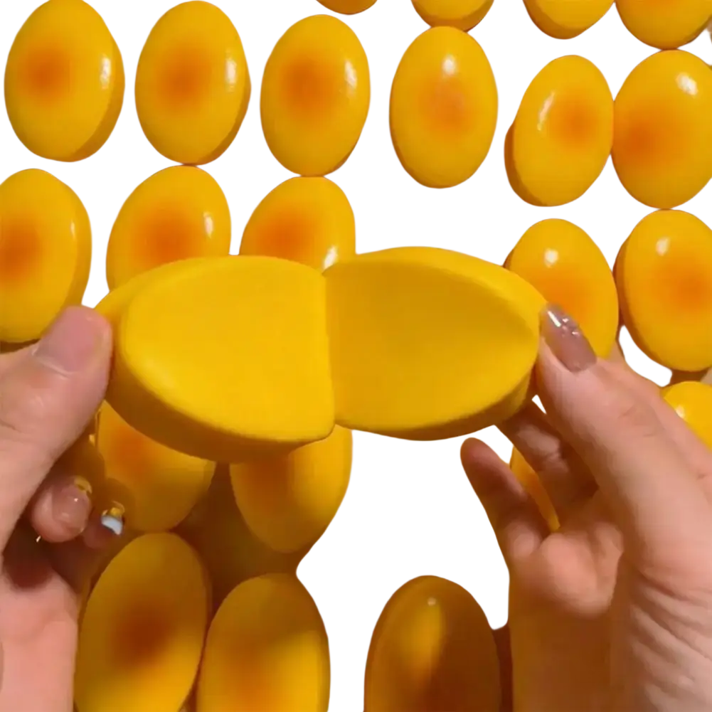 Bright yellow oval silicone egg mold with glossy finish and orange center for stress relief slow rising cheese cake squishy toy