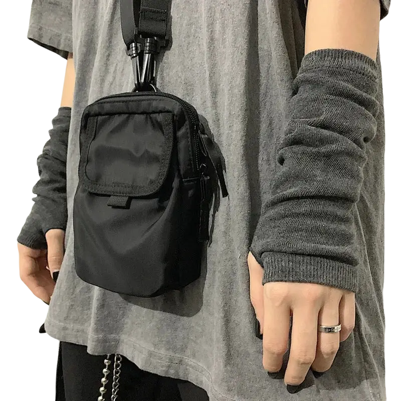 Black nylon crossbody bag with adjustable strap and front zippered pocket complementing striped knit fingerless arm warmers