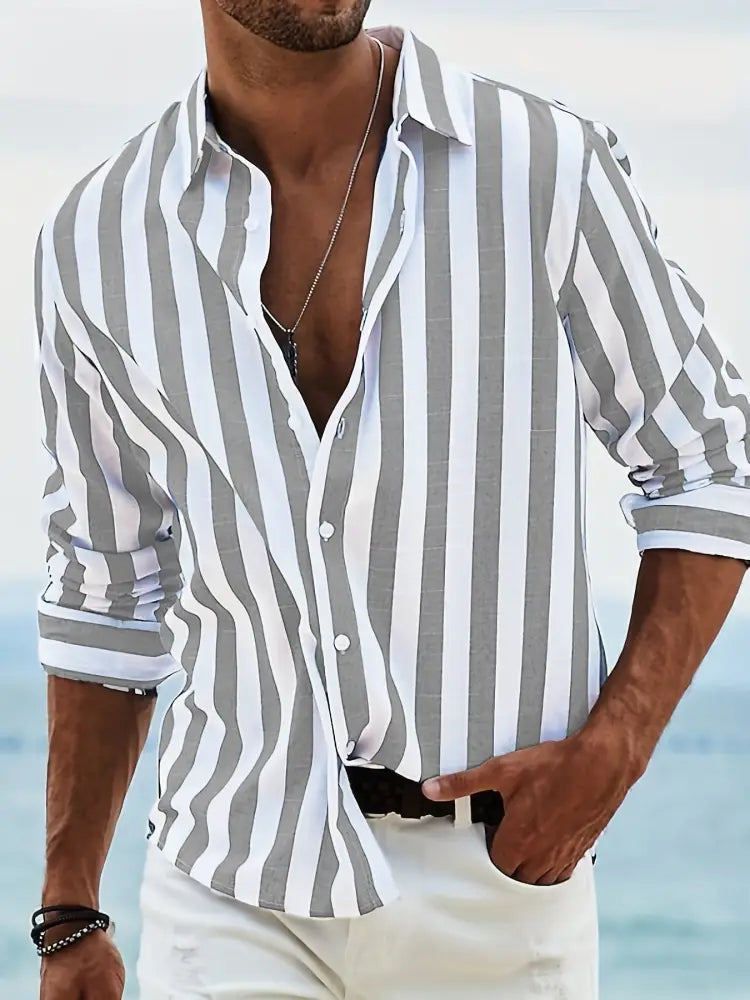 A man wearing a men’s loose fit vertical striped gray and white long sleeve casual button-down shirt with rolled-up sleeves