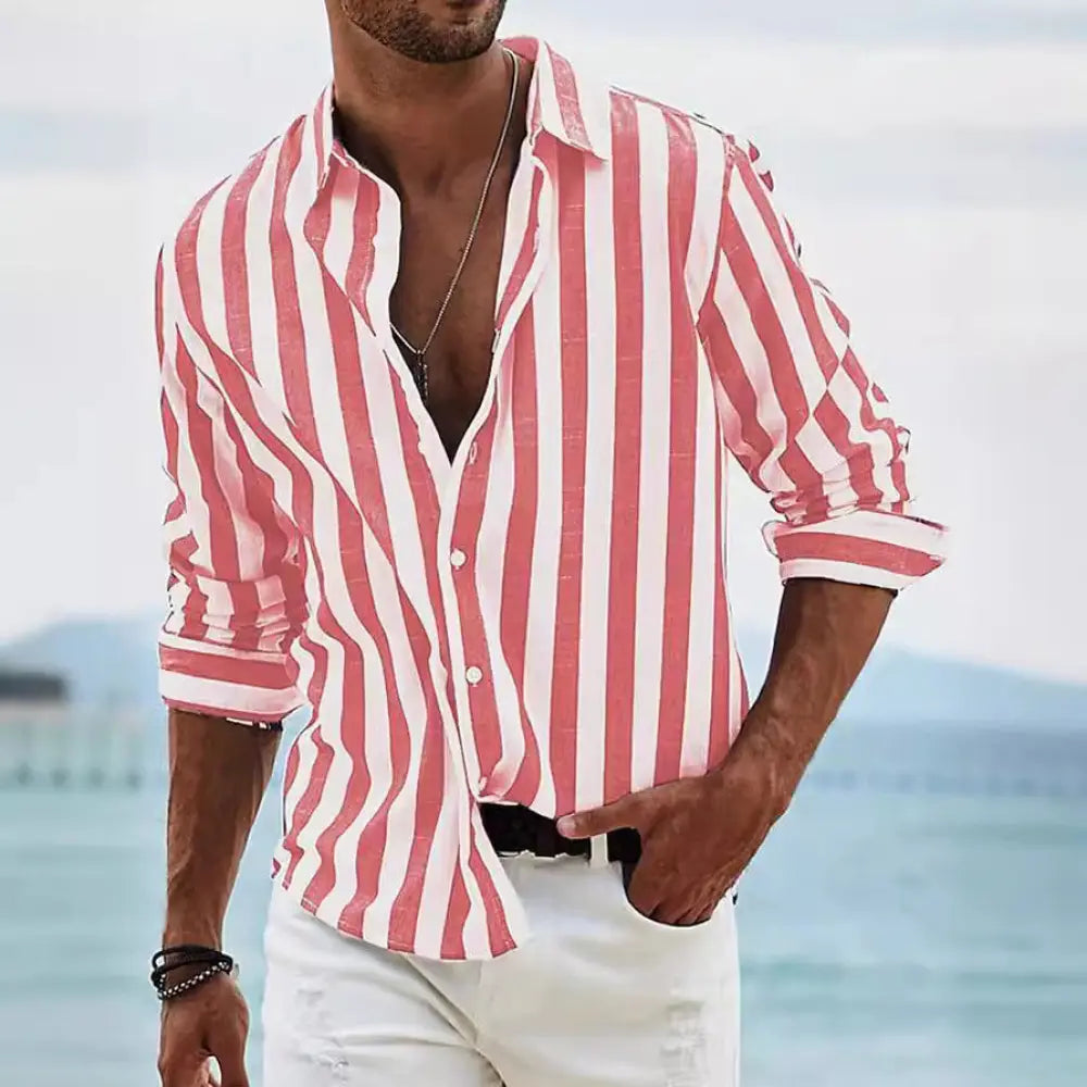 A man wearing a men’s loose fit vertical striped pink and white long sleeve casual button-up shirt with rolled sleeves