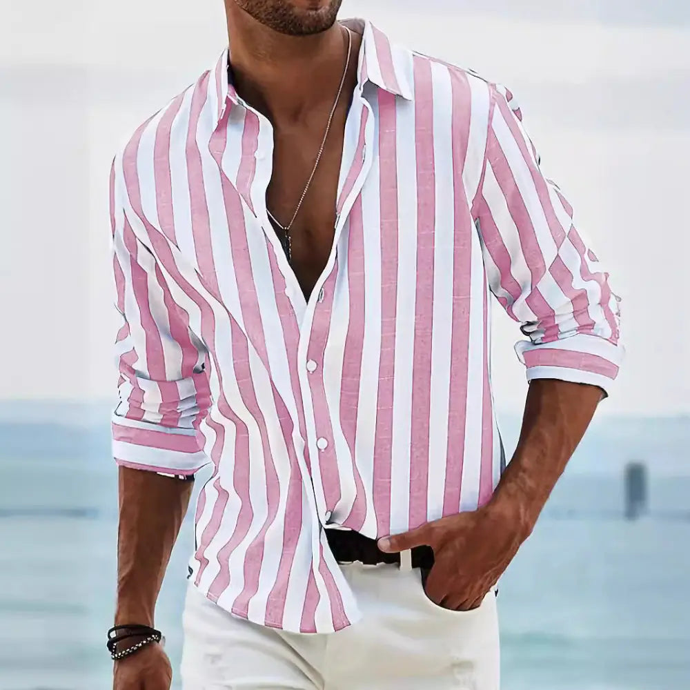 A man wearing a men’s loose fit vertical striped long sleeve casual shirt in pink and white with rolled sleeves