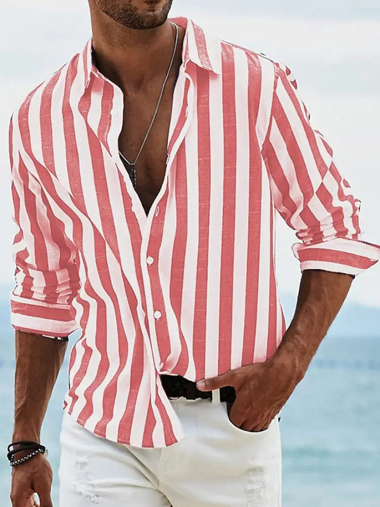 A man wearing a men’s loose fit vertical striped long sleeve casual shirt in pink and white with rolled sleeves