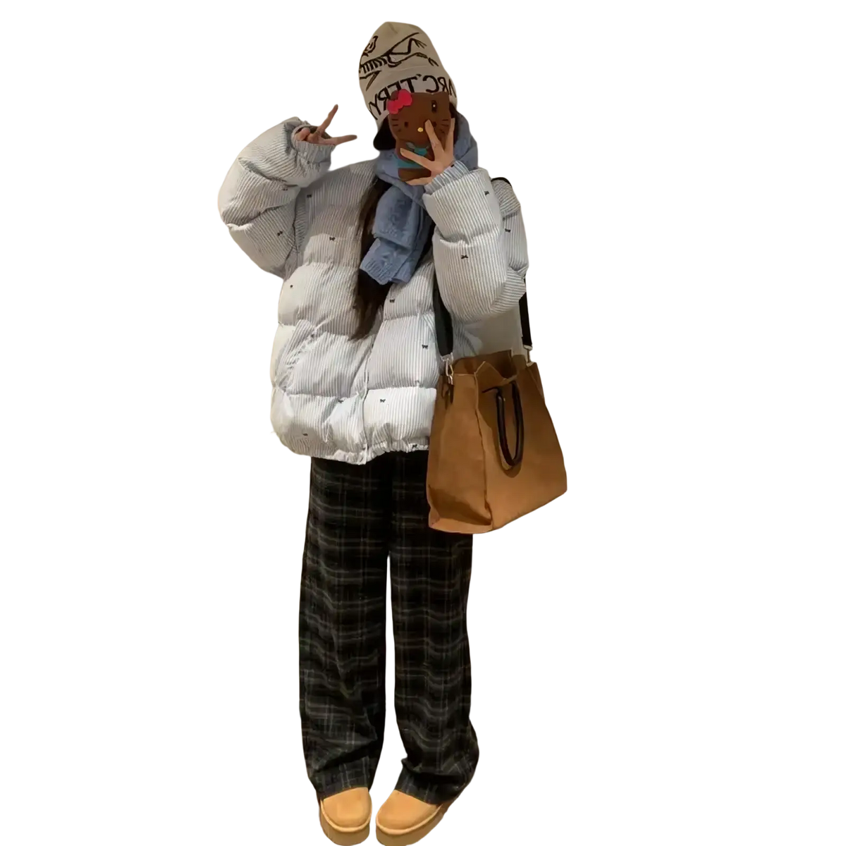 Tan canvas tote bag with black leather handles shown alongside striped puffer jacket winter coat product display