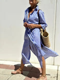 Blue and white vertically striped cotton shirt dress with button-up front side slit and rolled sleeves in linen style