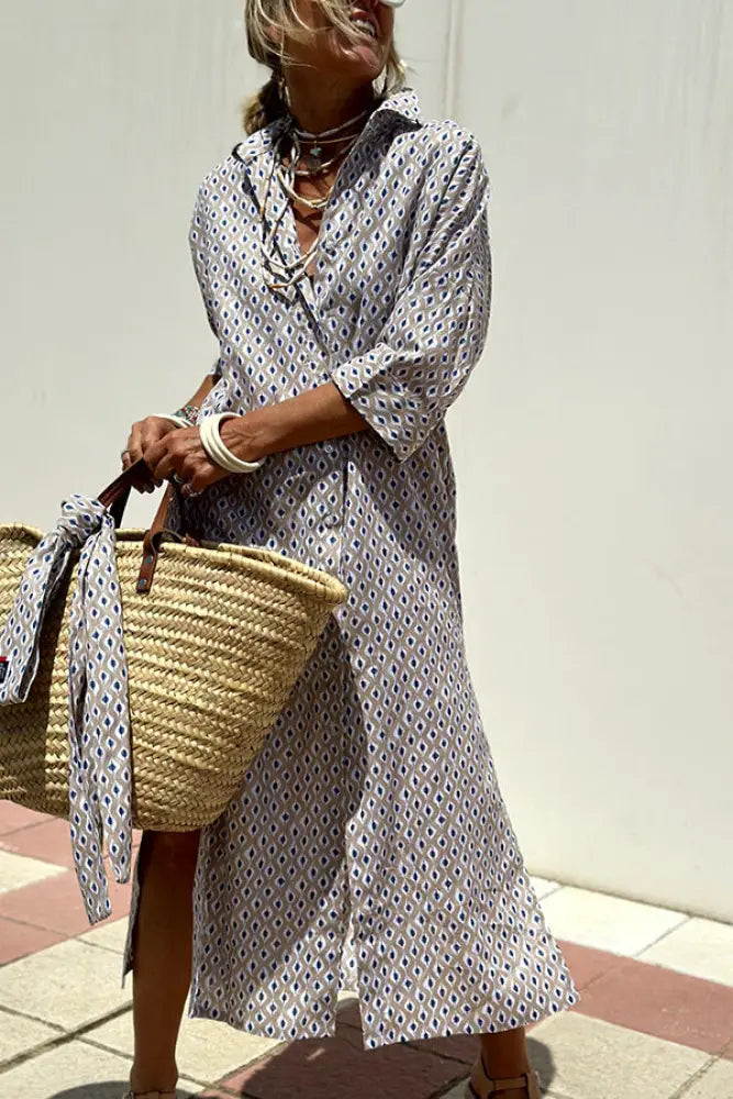 A woman wearing a long light gray and white striped linen belted lapel shirt dress with short sleeves