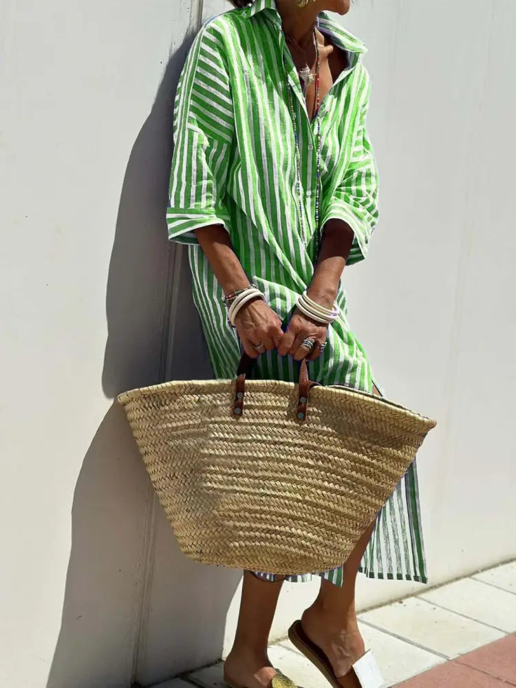 A woven straw tote bag with brown leather handles paired with a striped linen belted lapel shirt dress