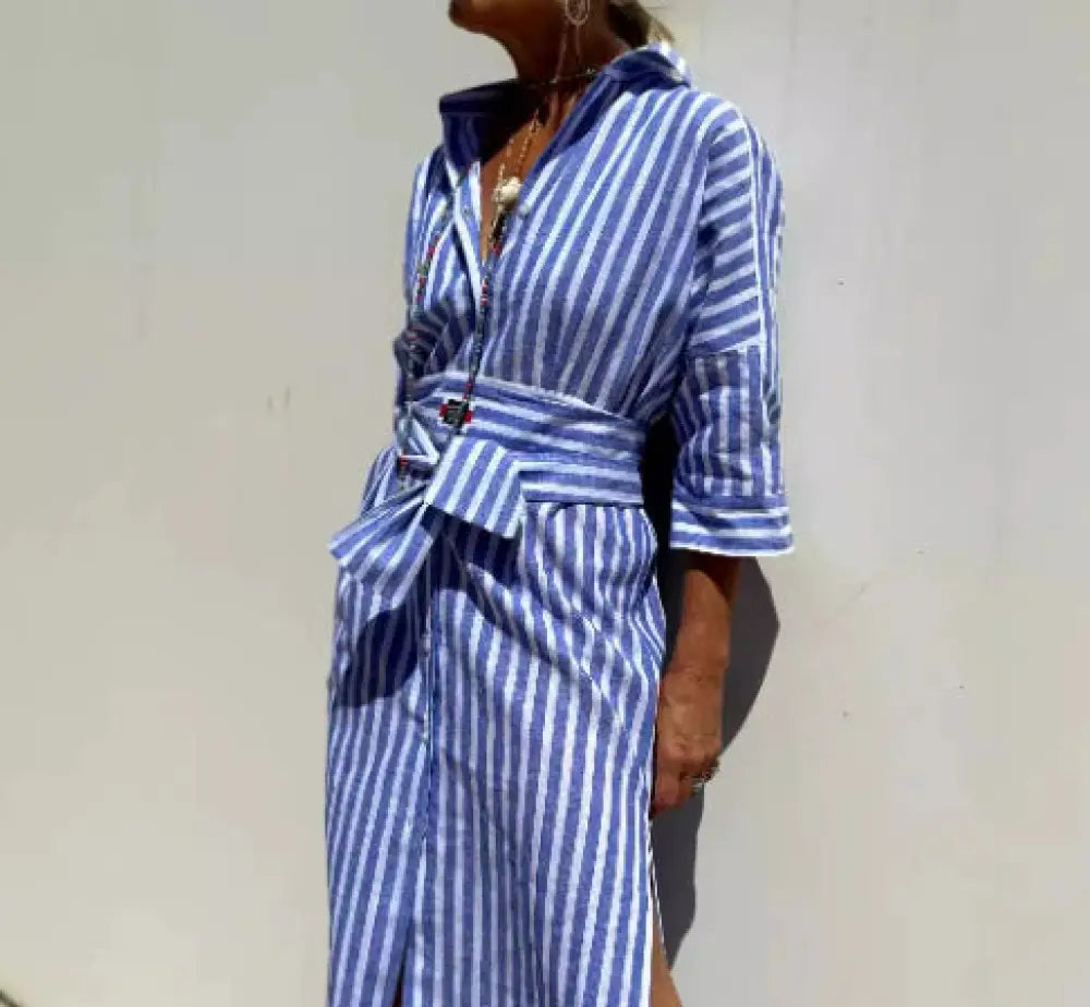 A blue and white striped linen shirt dress with collar three quarter sleeves and a self tie belt