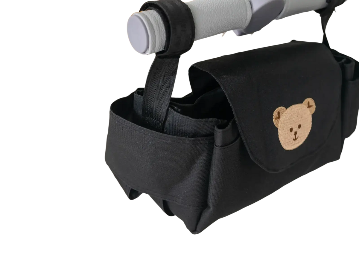 Black fabric stroller organizer bag featuring a beige embroidered bear face design for convenient storage