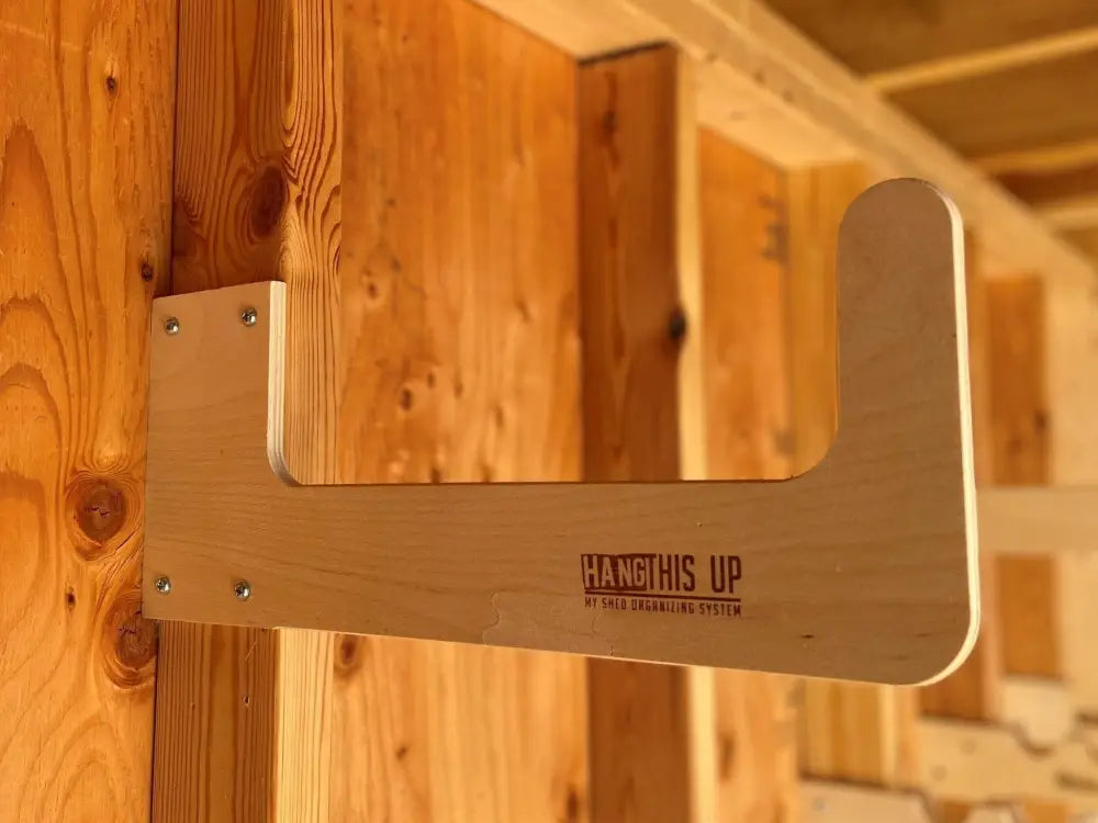Light-colored wooden stud mounted bike rack with minimalist design and hang this up branding engraved on surface