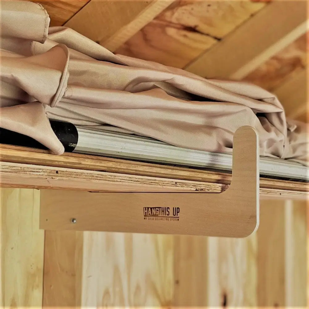 Light-colored wooden shelf bracket with engraved hang this up branding for stud mounted wood and pipe shed storage hooks