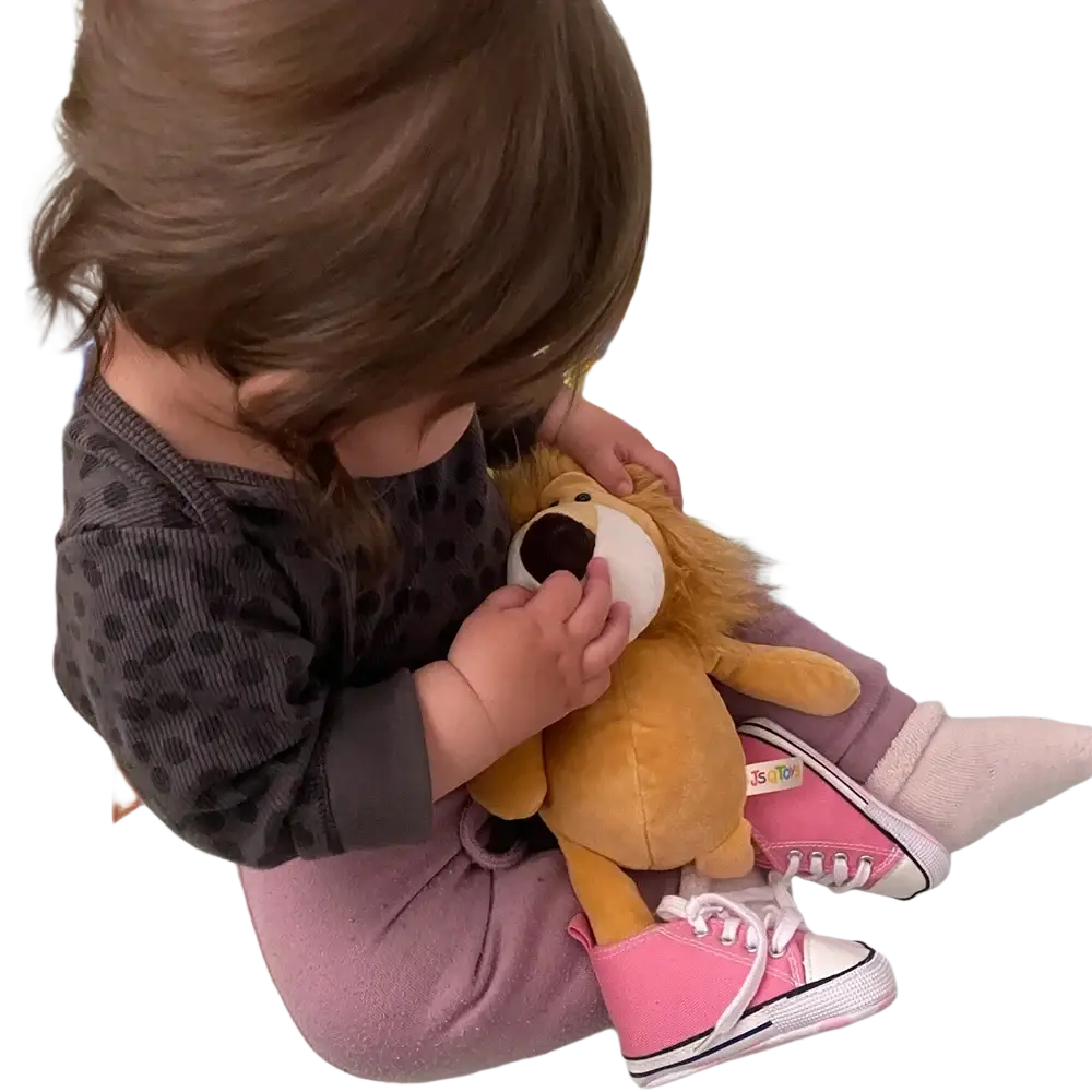 A plush golden lion stuffed animal with a white face and black nose held by a child from lion elephant tiger toys